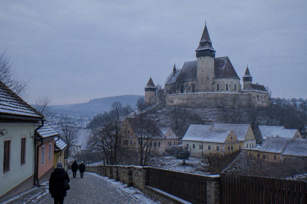 The fortified church tower of Biertan village under a grey winter sky with bare trees