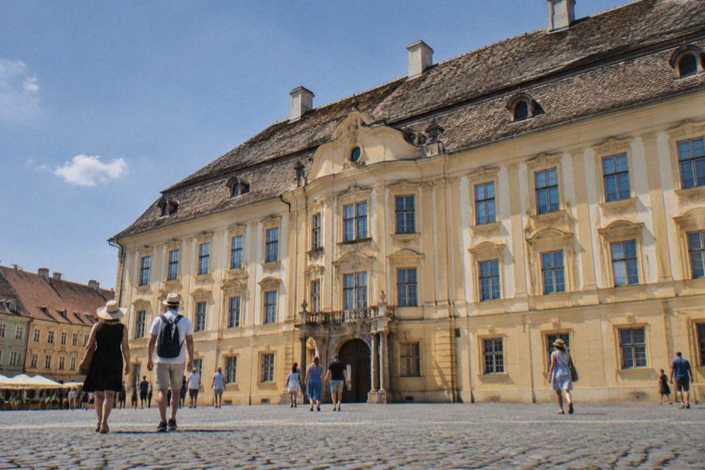 Visitors walking past the Brukenthal Palace facade on Piața Mare