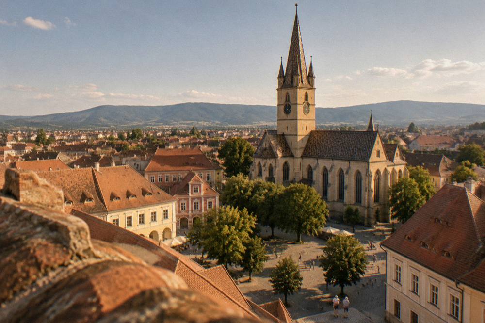 Aerial view of Sibiu's red rooftops and the Evangelical Cathedral tower in summer light