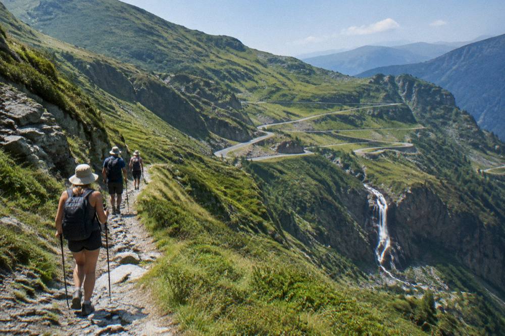 Hikers on a mountain trail above a waterfall in the Făgăraș mountains