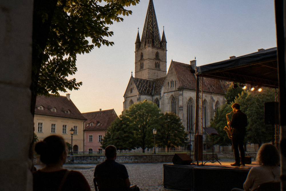 A musician playing a saxophone on a small stage in a stone courtyard at dusk
