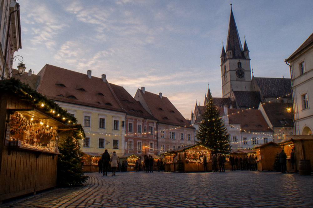 A festive market square at dusk with wooden stalls and string lights