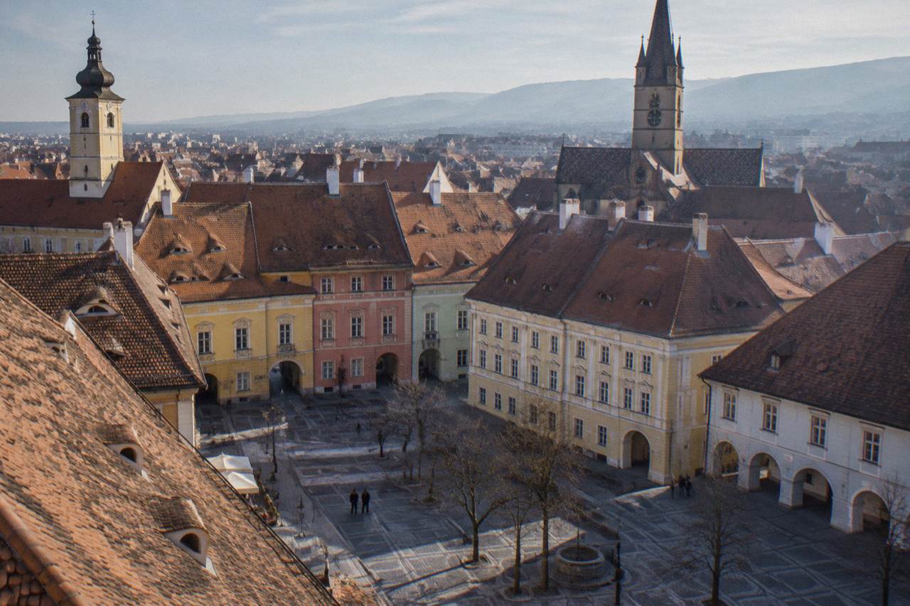 Colourful baroque facades and church towers seen across the rooftops of Sibiu's old town
