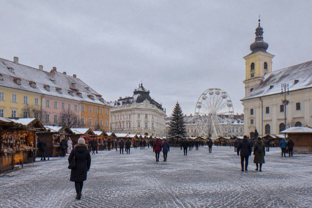 Christmas market stalls and a ferris wheel in a Romanian town square