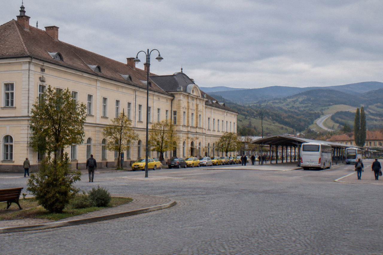 A long distance road curving through green Transylvanian hills toward distant mountains
