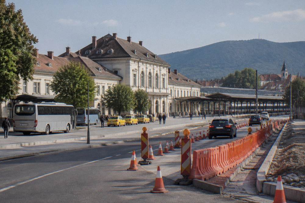 A highway roadworks zone with orange barriers and traffic cones narrowing two lanes