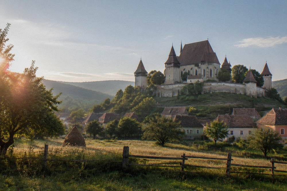 A fortified church with thick defensive walls in a Transylvanian village meadow