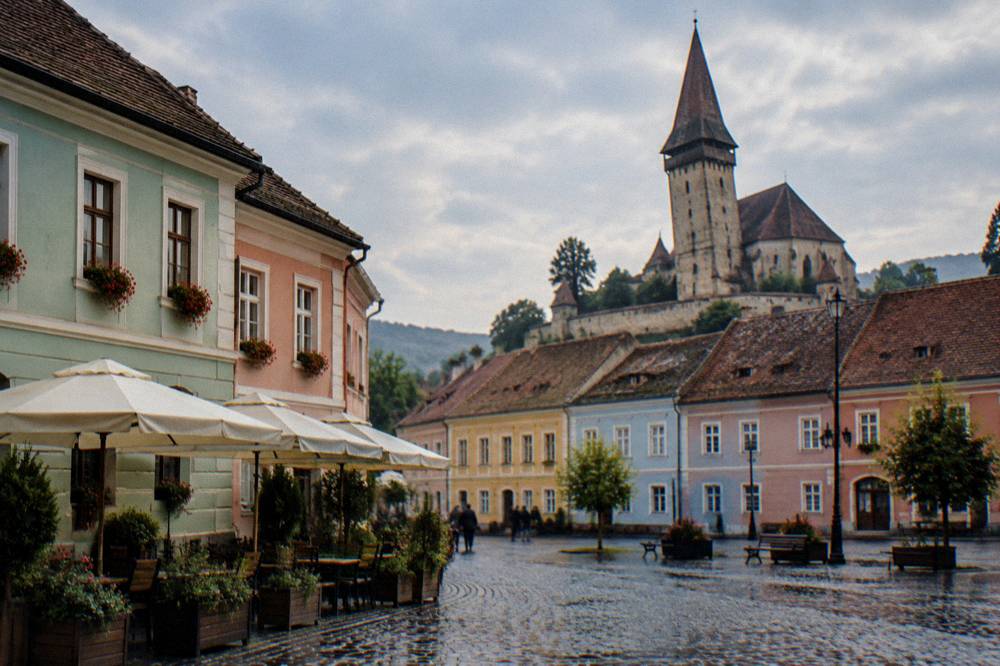Pastel-coloured merchant houses on a cobbled square in Mediaș