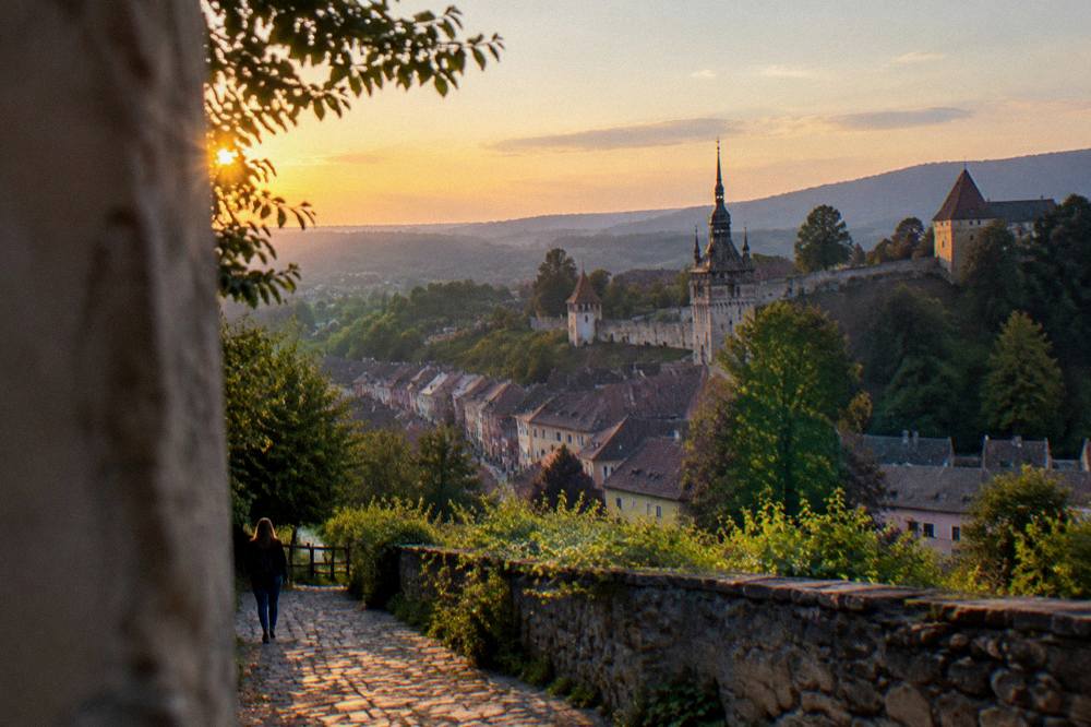 The walled skyline of Sighișoara seen from a hillside path at sunset