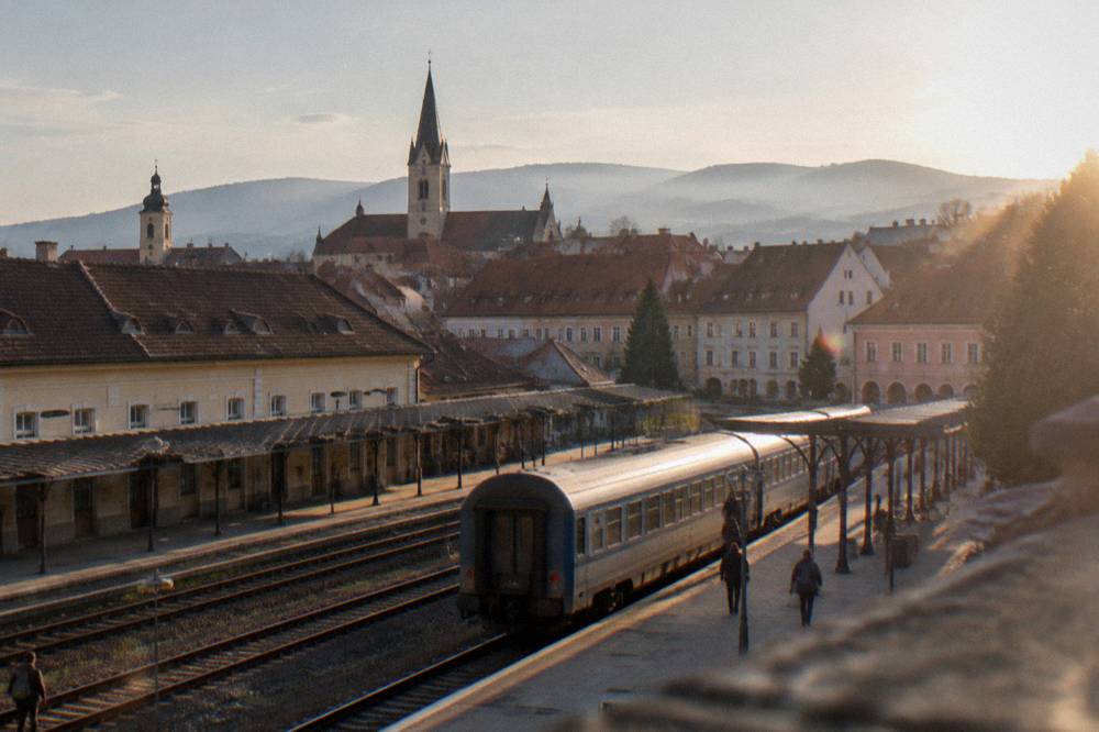 A passenger train at a platform in Sibiu station seen along the tracks