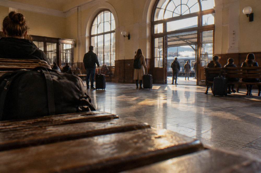 Travellers waiting with bags in the ticket hall of a small Romanian train station