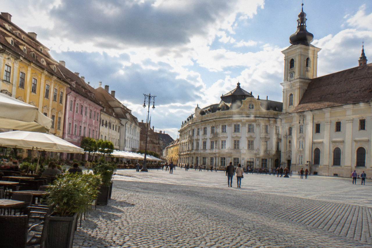 Colourful baroque houses and cafe terraces around a large square in Sibiu on a bright day