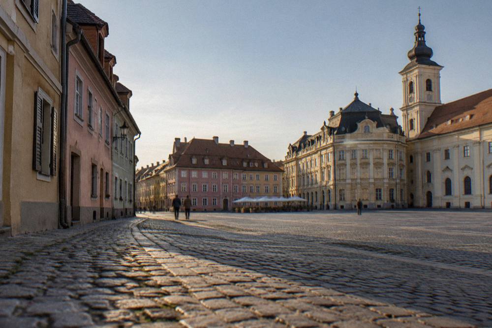 A narrow cobblestone lane in Sibiu's lower town with pastel houses and steep dormer windows