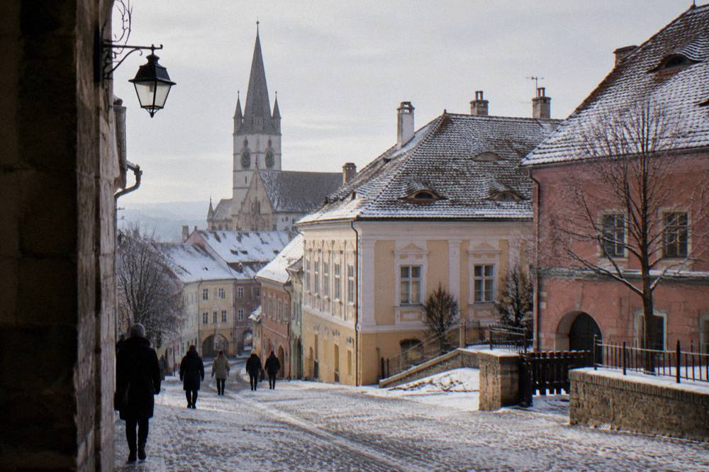 Colourful baroque buildings and a church spire along a cobbled street in winter light
