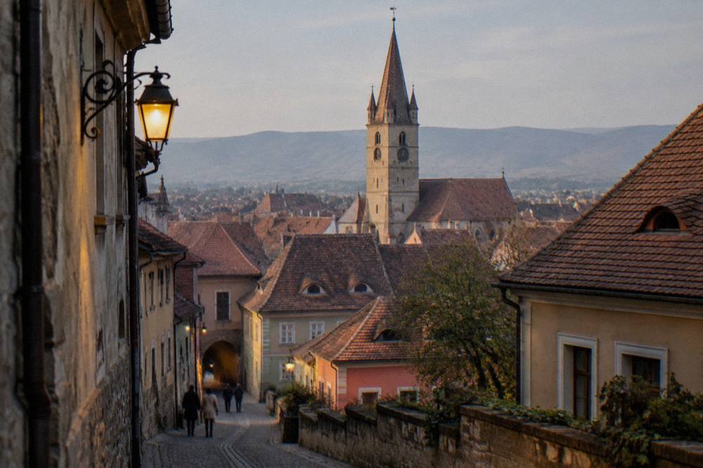 A medieval clock tower rising above red-tiled roofs inside a walled town
