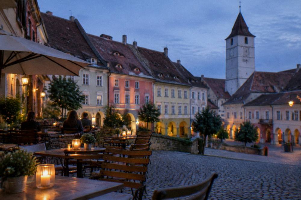 An evening restaurant terrace on a cobbled square with candles and half-timbered facades