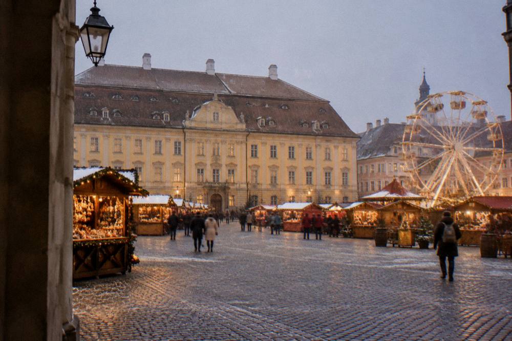 A golden medieval square lined with stalls and a ferris wheel under dusk lights