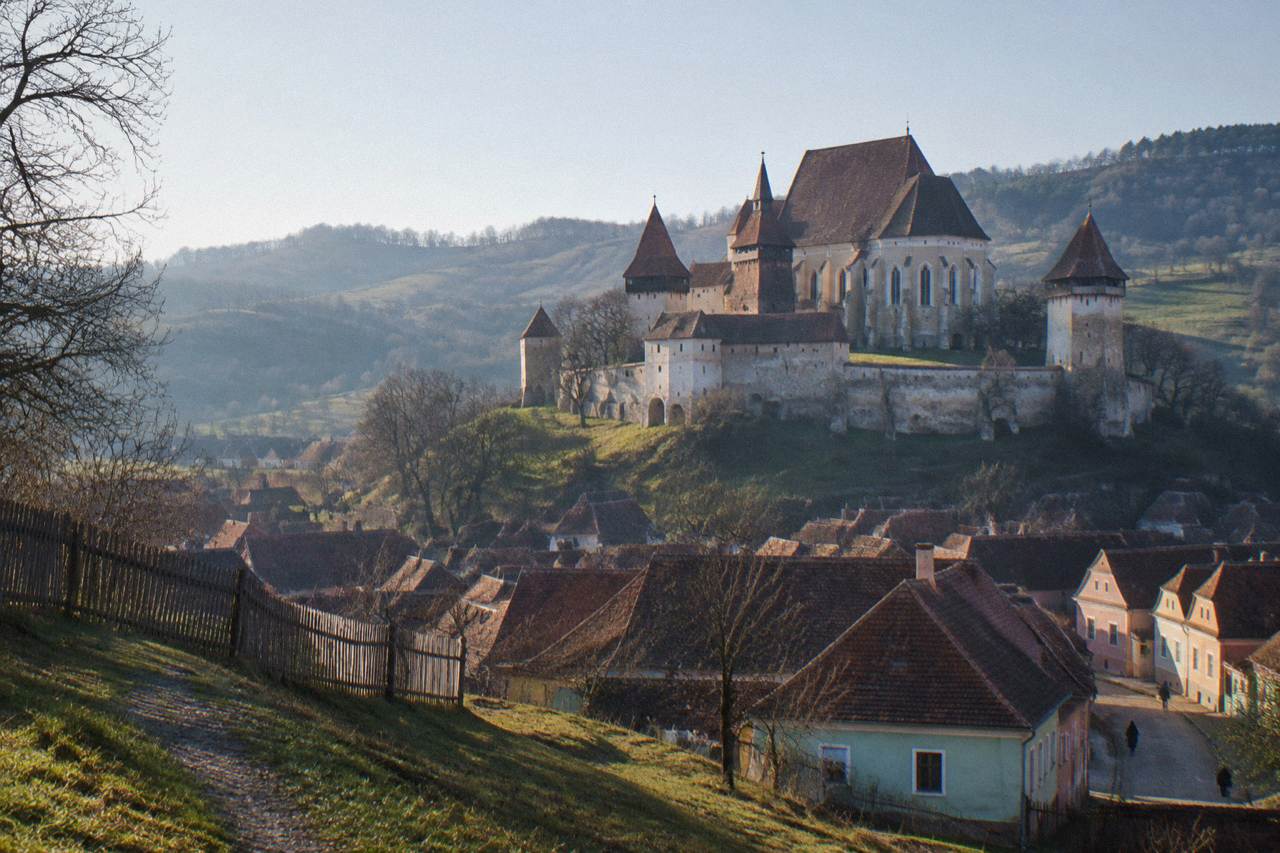 Fortified church with towers rising above a Transylvanian village and green hills