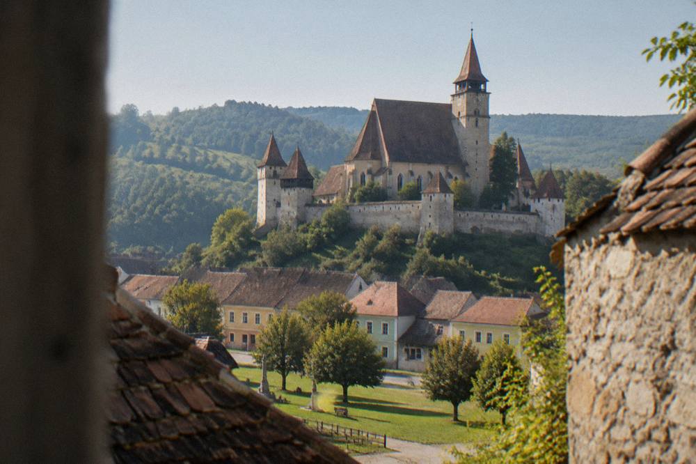 Stone defensive wall and church tower of a fortified Saxon church above a village green