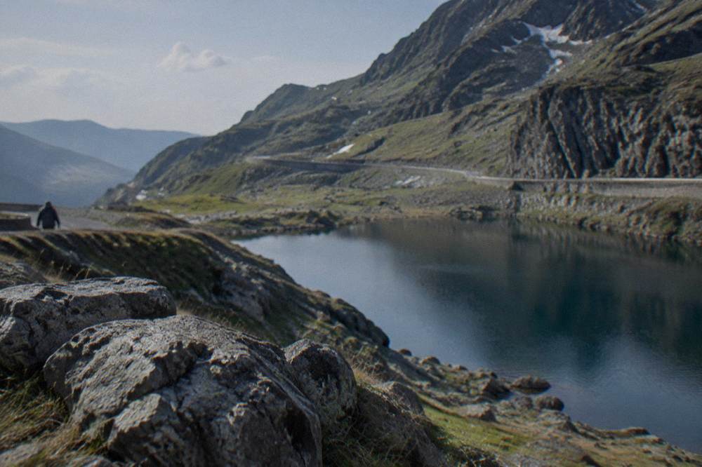 A glacial lake ringed by steep rocky slopes near the top of a mountain road