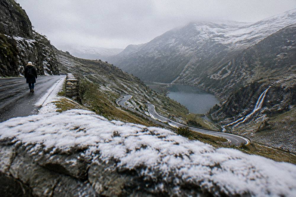 A mountain lake and steep road under a dusting of early autumn snow