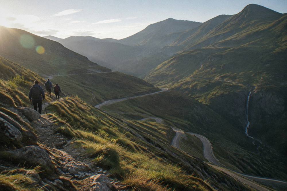 Hikers in jackets walking a mountain path above a deep valley
