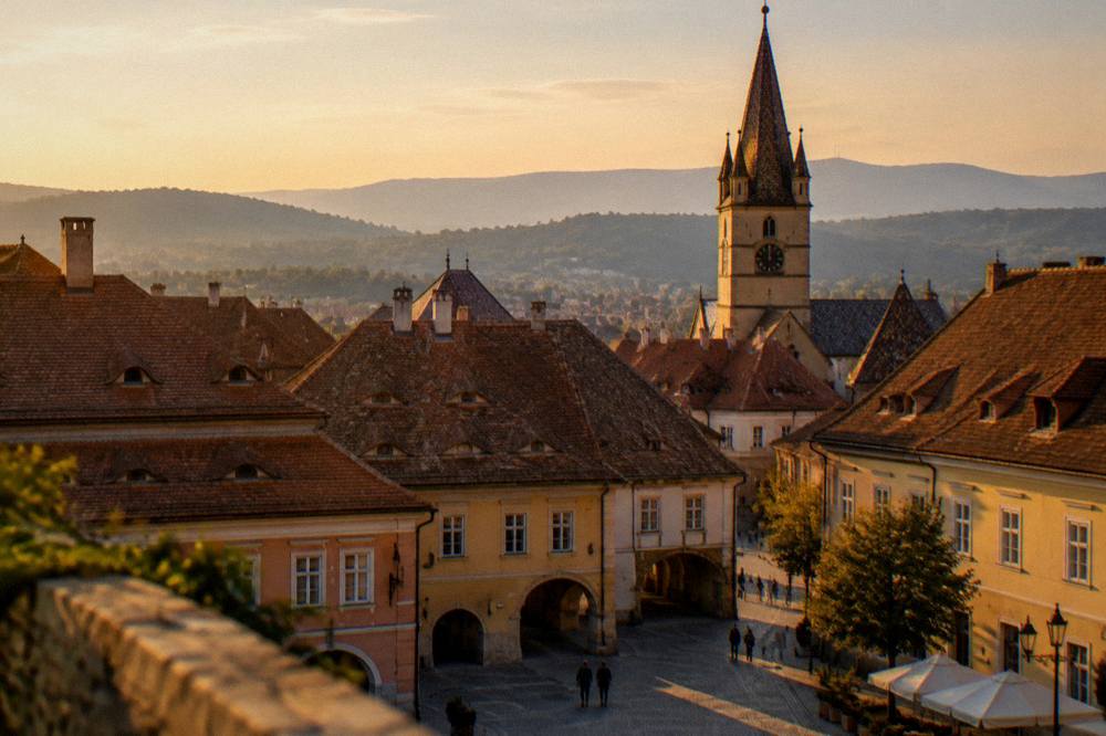 Rooftops of Sibiu old town with dormer windows and distant hills under evening sky