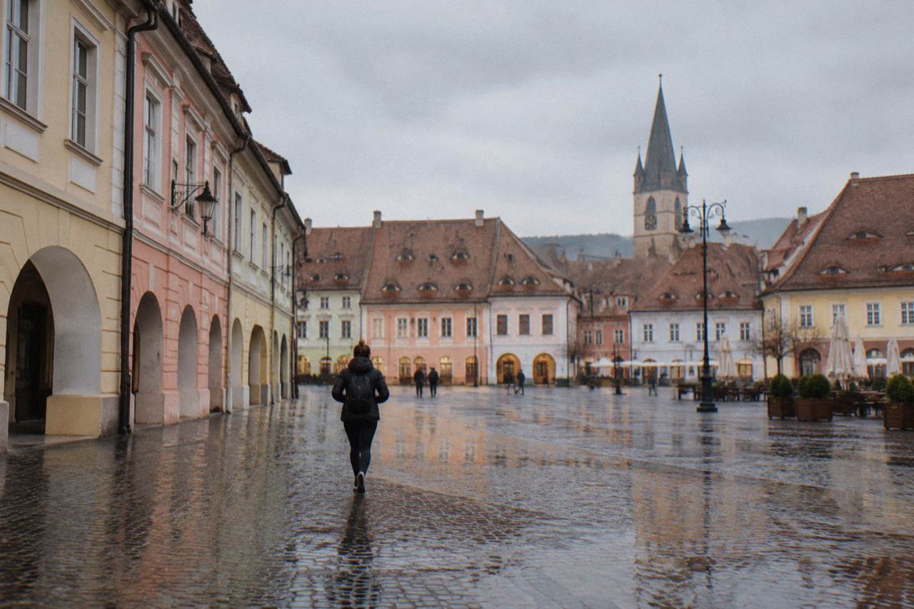 Wet cobblestone square in Sibiu old town with colourful facades reflecting in puddles