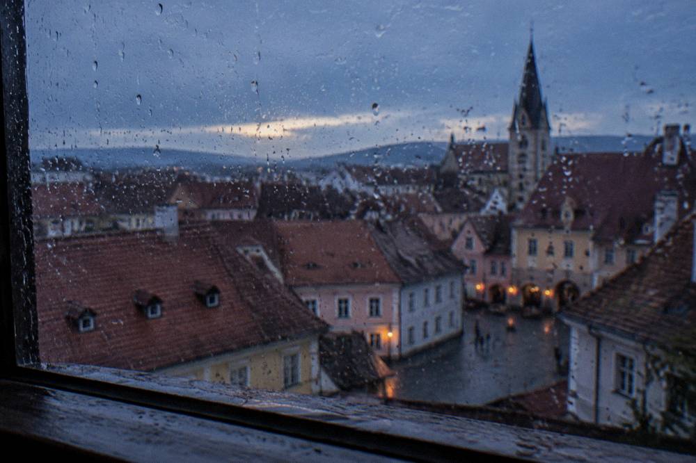 Raindrops on a window pane with blurred historic Sibiu rooftops beyond