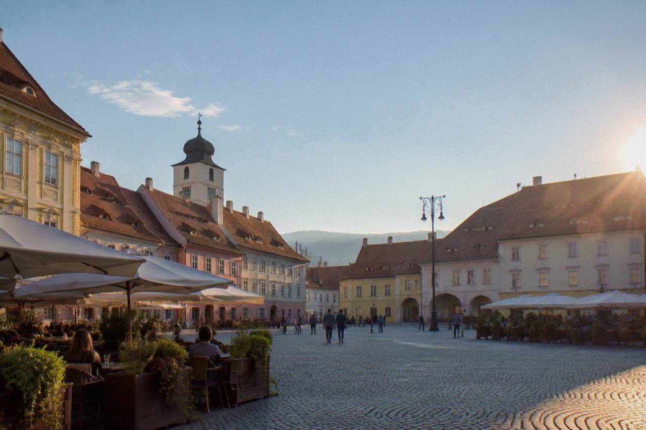 Colourful baroque houses and cafe terraces around the grand square of a Transylvanian old town