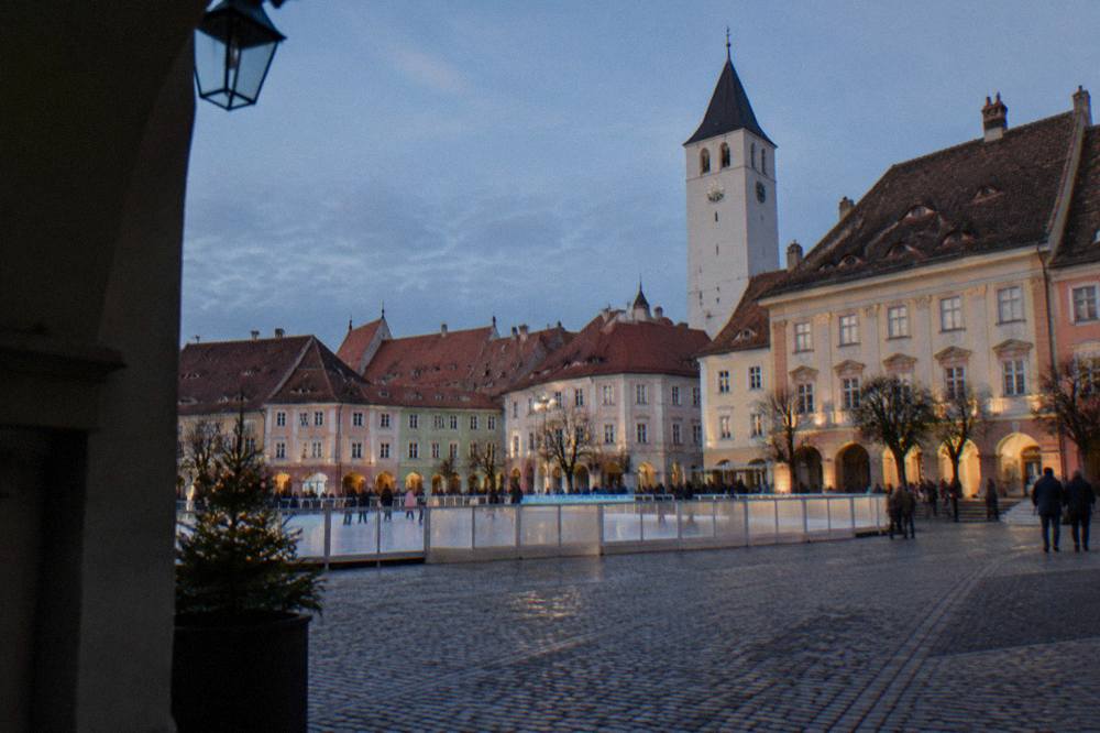 A grand square lined with pastel-coloured buildings and an ice rink in front of a museum palace