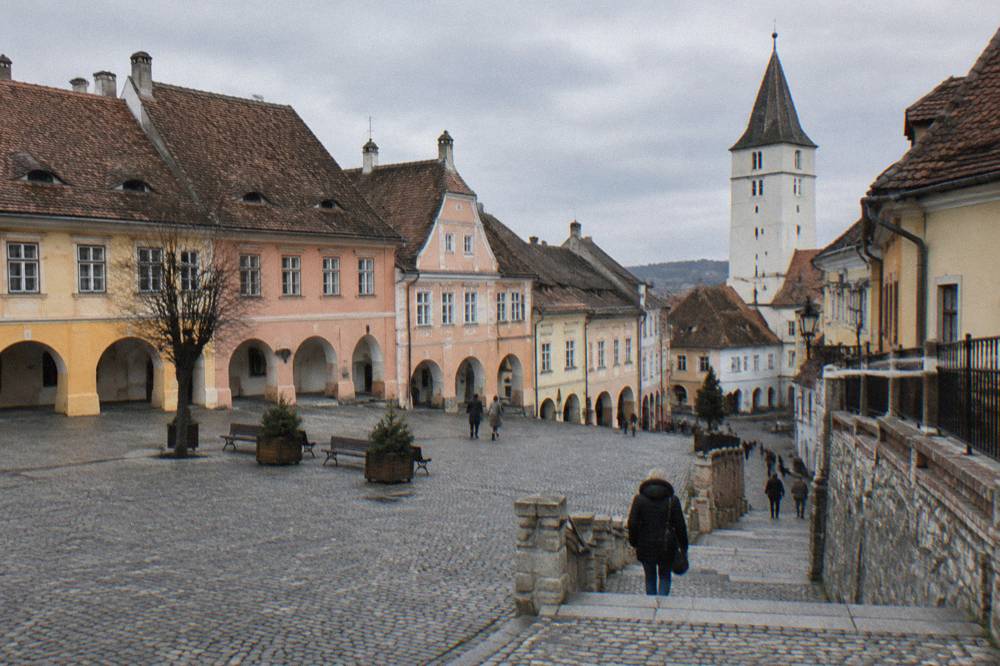 A narrow passage of stone stairs connecting an upper square to a lower town street