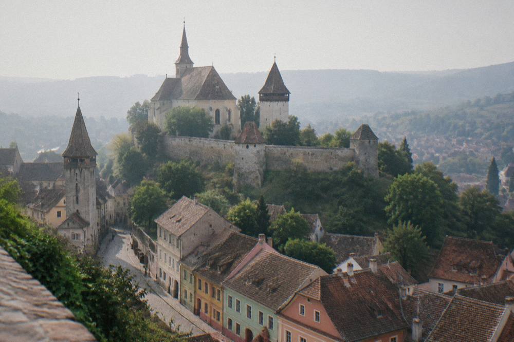 A fortified Saxon church with high walls and towers standing above a Transylvanian village