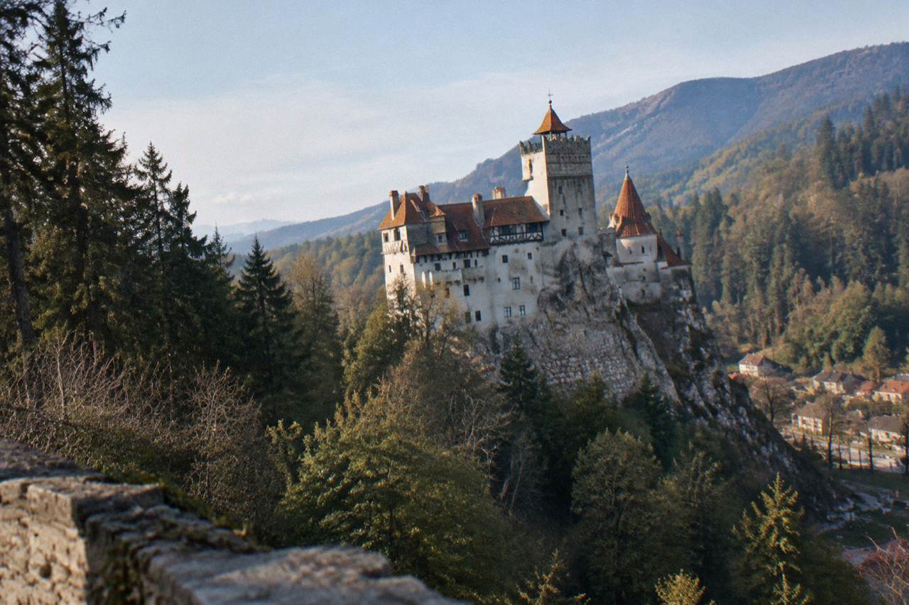 Bran Castle rising on a forested cliff above the village at the entrance to a mountain pass