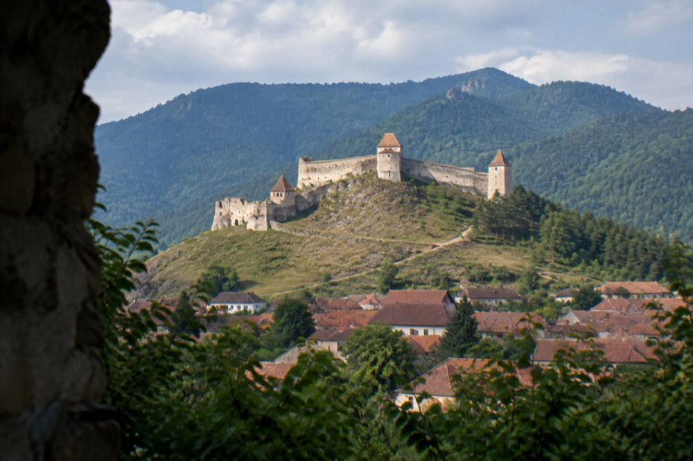 Râșnov fortress walls on a hilltop above a village with the Carpathians behind