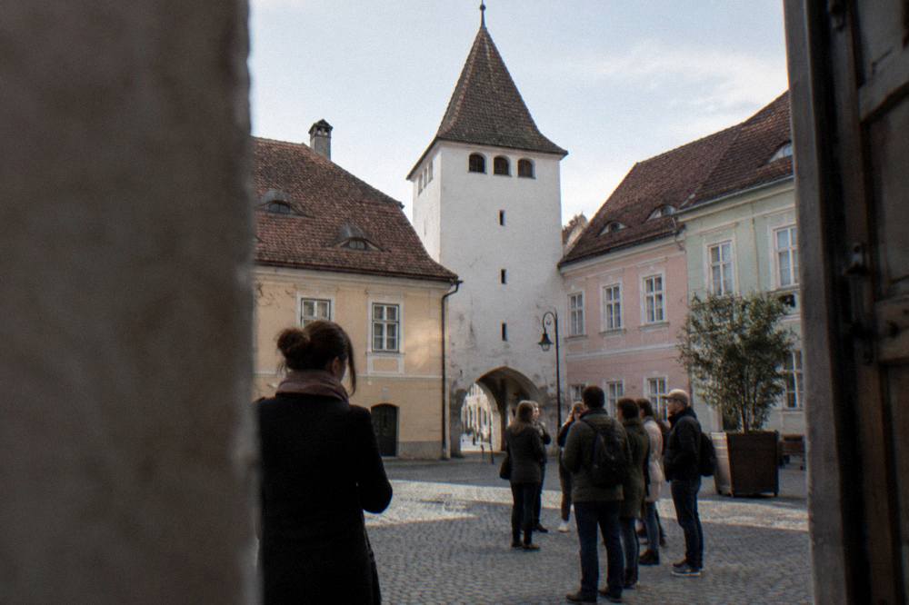 A guide concluding a walking tour as the group tips the guide beside the Council Tower in Sibiu