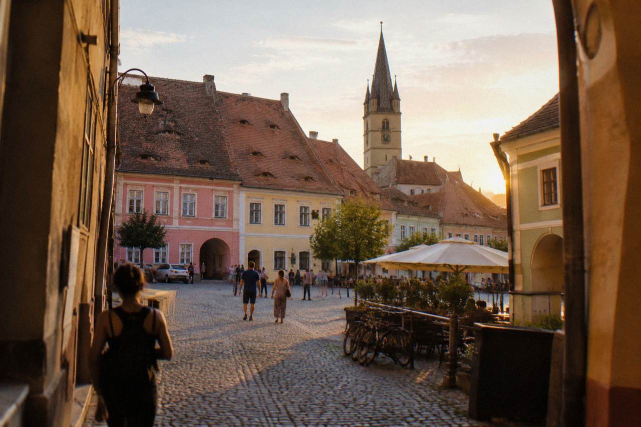 Colourful historic houses with steep red roofs and small attic windows above a cobbled square in Sibiu