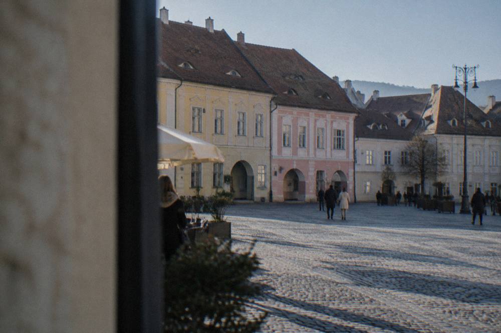 A pedestrian square in Sibiu lined with pastel-coloured baroque buildings under a clear sky