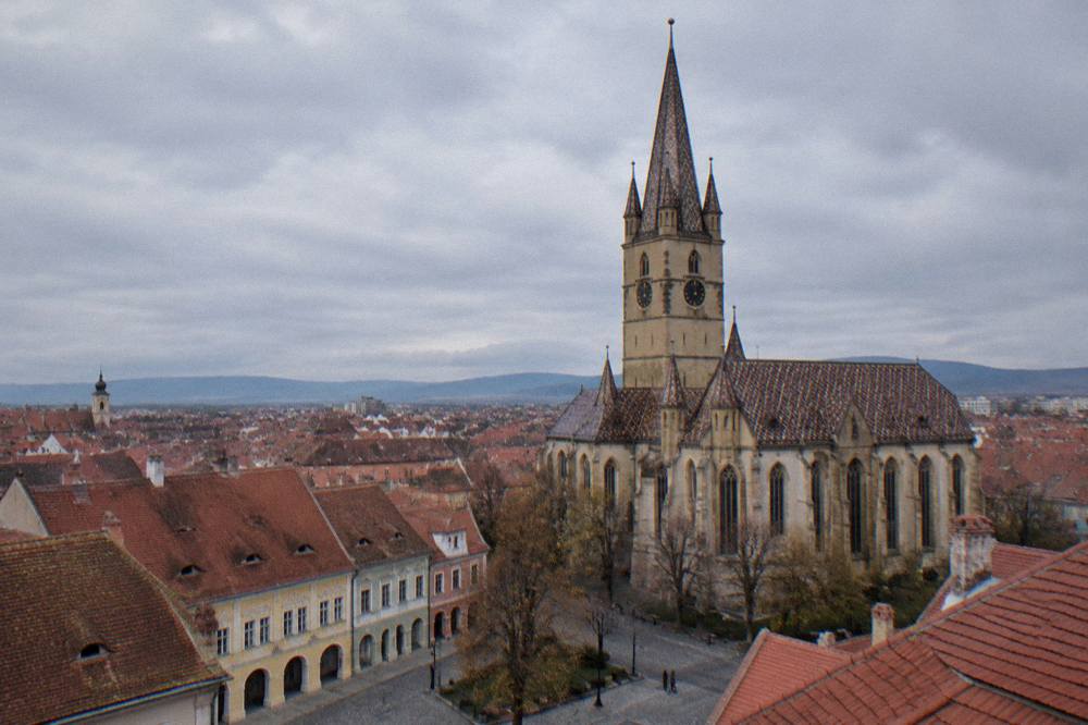 A wide view over the red rooftops of Sibiu with the Evangelical Cathedral tower rising above the old town