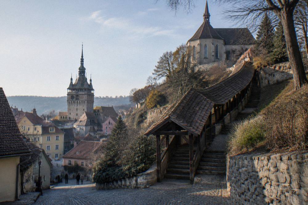 A covered wooden staircase climbing toward a church above the Sighișoara citadel