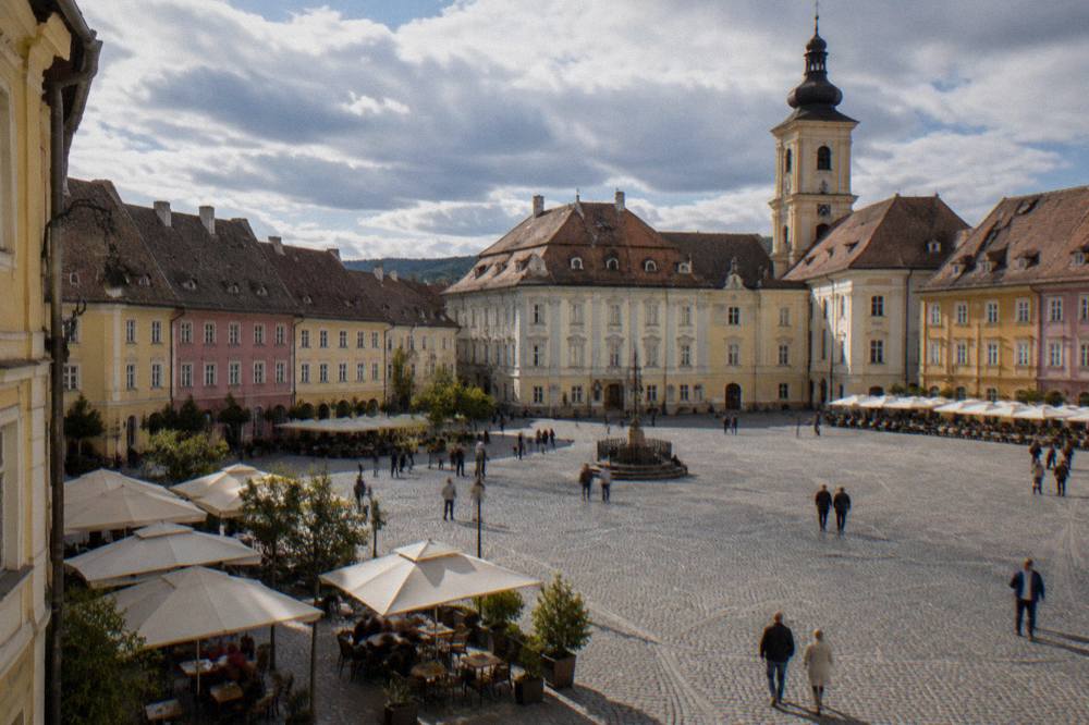 The main square of the Sighișoara citadel with outdoor tables and historic buildings