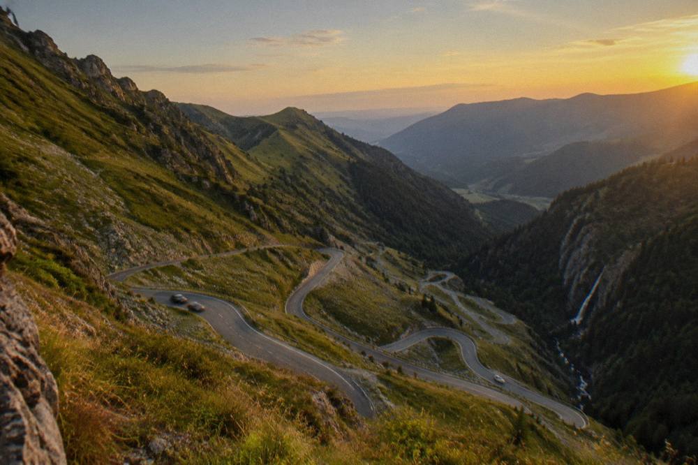 Hairpin bends of an alpine road seen from above with forested slopes